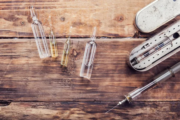 Uma seringa e ampolas de medicamento na mesa de madeira — Fotografia de Stock