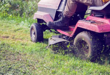 Fresh cut grass flying from riding lawnmower person cutting long green grass with a riding lawn clipart