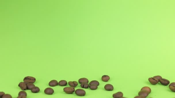 Falling coffee beans on heap of coffee beans on a green screen — Stock Video