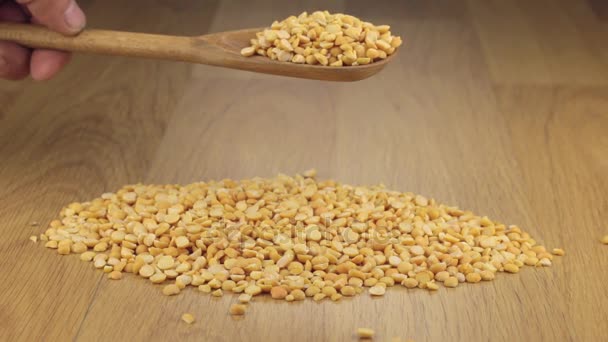 Les grains secs de pois dorment assez d'une cuillère en bois sur une pile de pois — Video