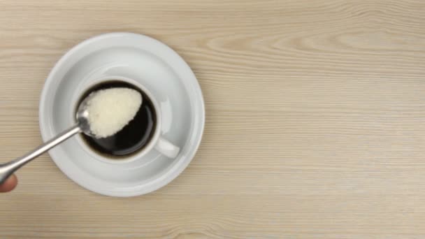 Рука кладе цукор ложкою в чашку кави і перемішує її — стокове відео