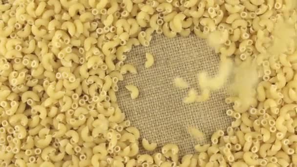 Fallande pasta på roterande cirkla av pasta liggande på säckväv. — Stockvideo
