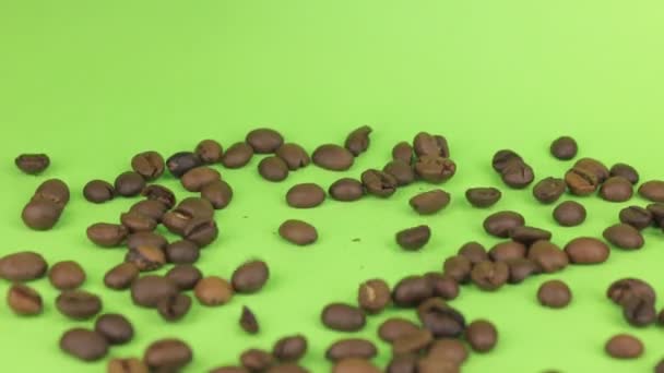 Caindo grãos de café em uma pilha de grãos de café em uma tela verde . — Vídeo de Stock