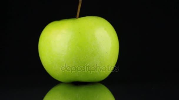 Rotating green apple and its reflection on a black background. — Stock Video