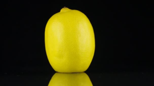 Rotating lemon and its reflection on a black background. — Stock Video