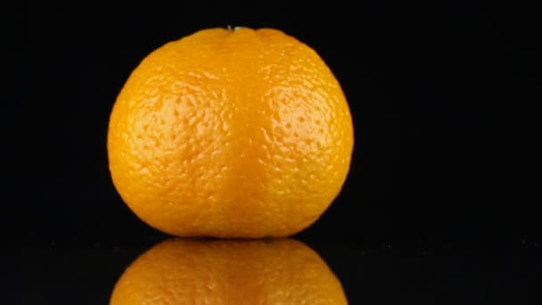 Mandarina giratoria, y su reflejo sobre un fondo negro . — Vídeos de Stock