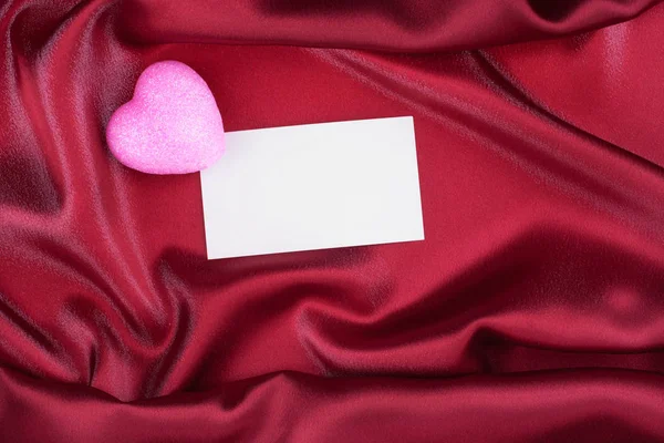 Ροζ καρδιά και κενό λευκό καρτ ποστάλ, αδειάστε καρτ-ποστάλ, έγκειται σε κόκκινο μετάξι. — Φωτογραφία Αρχείου