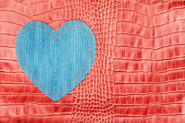 Heart made of denim, lies on the red crocodile skin. — Stock Photo, Image