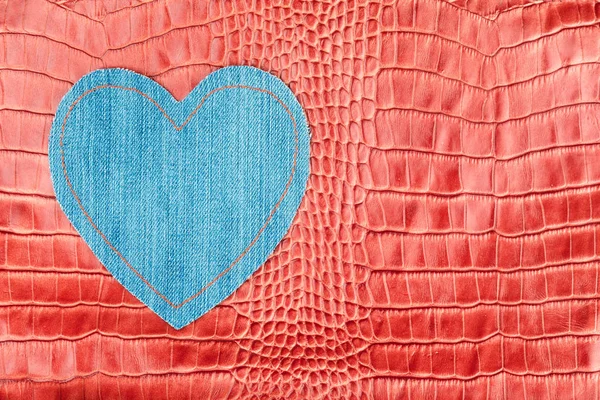 Cuore realizzato in denim, giace sulla pelle di coccodrillo rosso . — Foto Stock