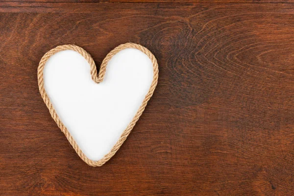 Touw in de vorm van een hart met een plek voor uw tekst, liggend op een houten oppervlak. — Stockfoto