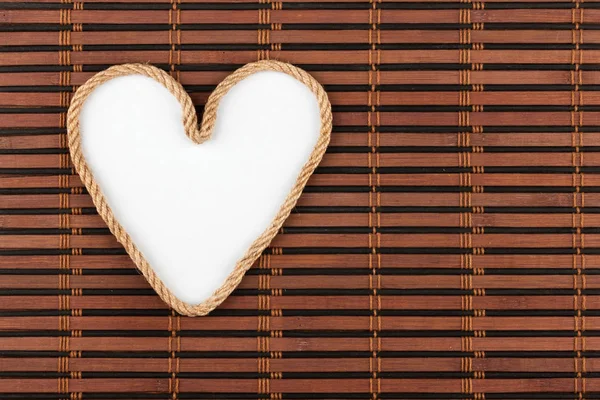 Corde en forme de cœur avec une place pour votre texte, couché sur un tapis de bambou . — Photo