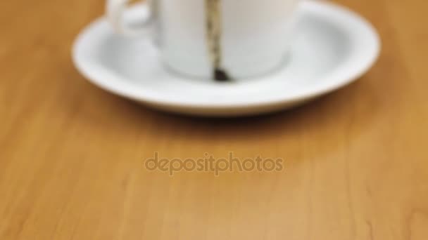Video einer weißen Tasse mit Kaffee liegt auf dem Tisch. Dollly erschossen. Nahaufnahme. — Stockvideo
