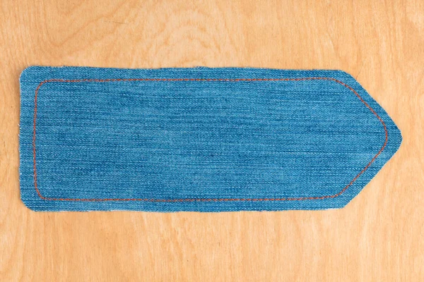 Pointer made from denim lying on a wooden surface. — Stock Photo, Image