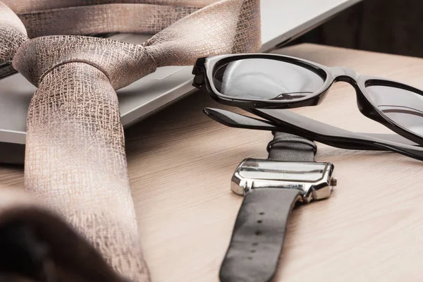 Mode en het bedrijfsleven. Close-up zonnebril, binden en bekijken, op een houten tafel — Stockfoto