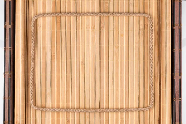Рамка з мотузки лежить на бамбуковому килимку з загорнутими краями . — стокове фото