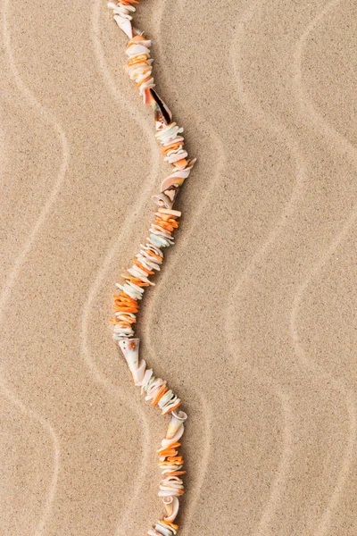 Collares hechos de conchas marinas yacen en la arena entre las dunas . — Foto de Stock