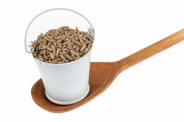 Full bucket of rye grains stands in a wooden spoon. — Stock Photo, Image