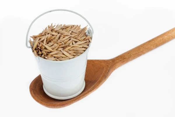 Full bucket of oat grains stands in a wooden spoon. — Stock Photo, Image