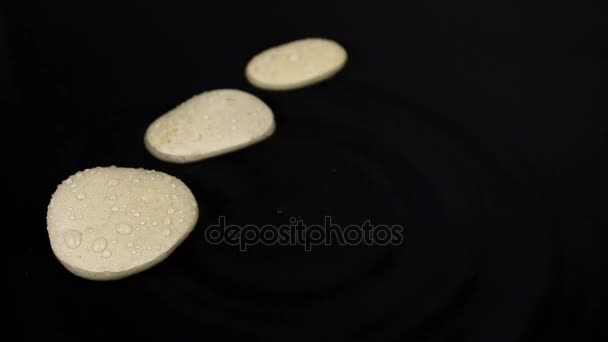 Cayendo gotas en el agua con una piedra blanca de tres, salpicaduras y olas . — Vídeos de Stock