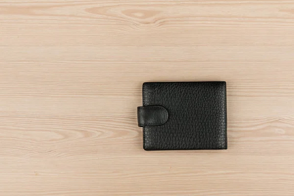 Black leather purse lying on a wooden table. — Stock Photo, Image