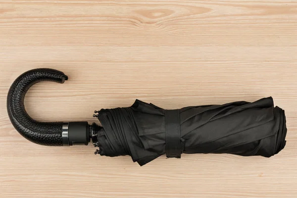 Składany czarny Parasol automatyczny leżącego na drewnianym stole. Obrazek Stockowy