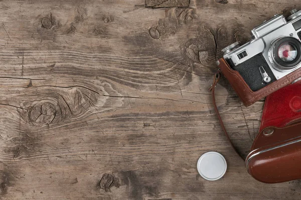 Retro camera in leather case on wooden background