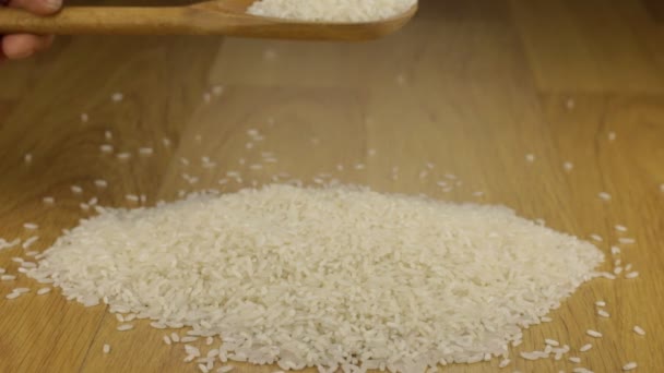 Main verse rapidement les grains de riz d'une cuillère en bois sur un tas de riz . — Video