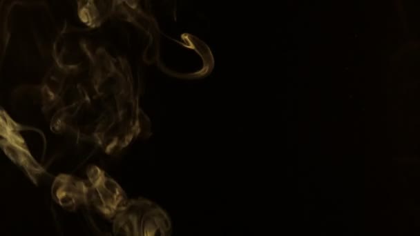 Gele rook in de vorm van ringen op een zwarte achtergrond. — Stockvideo