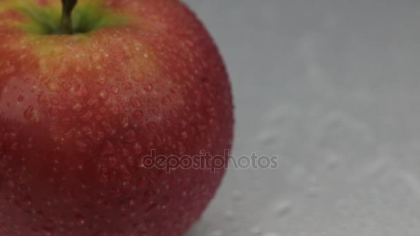 Wind blows away the drops of water from a rotating red apple. — Stock Video