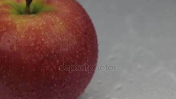 El viento sopla las gotas de agua de una manzana roja giratoria . — Vídeo de stock