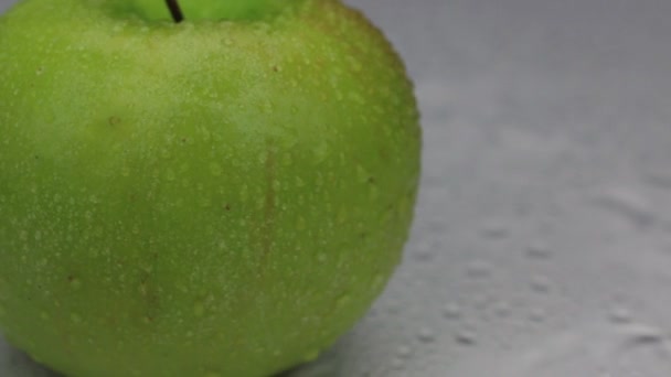 Vinden blåser bort dropparna vatten från ett roterande grönt äpple. — Stockvideo