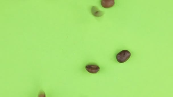 Πτώση κόκκους καφέ σε μια περιστρεφόμενη πράσινη οθόνη, απομονωμένο. — Αρχείο Βίντεο
