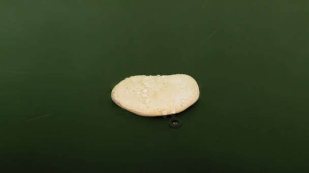 Närmar sig en droppe vatten är bruten på en vit sten liggande i grönt vatten. — Stockvideo