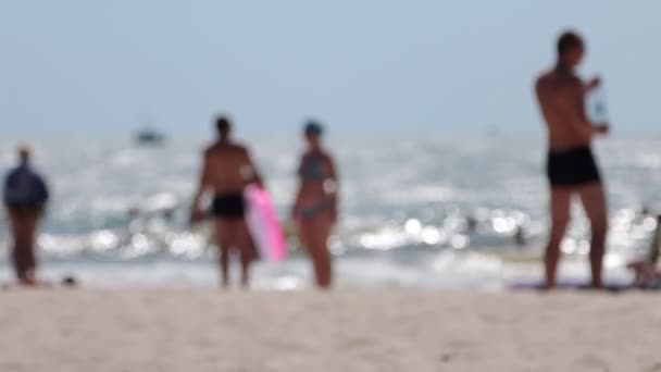 Vista borrosa de la playa desde la playa y en el mar con un barco flotante y la chica que pasa en primer plano . — Vídeos de Stock