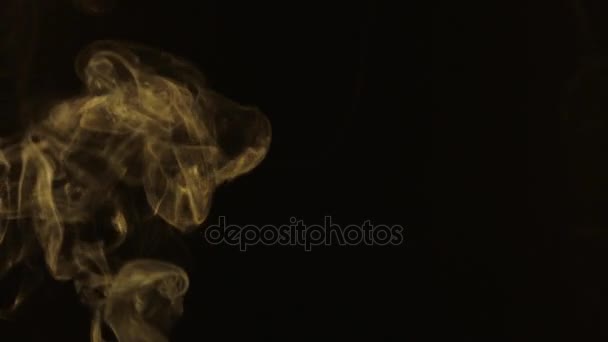 Beautiful stream of yellow smoke turns into swirls on a black background. — Stock Video