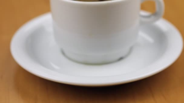 Video einer weißen Tasse mit Kaffee liegt auf dem Tisch. Dollly erschossen. Nahaufnahme. — Stockvideo