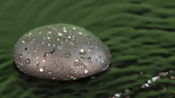 Vento sopra em uma gota caindo na água verde e uma pedra preta . — Vídeo de Stock