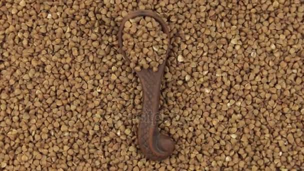 Rotation av en lera sked med bovete liggande på en hög av bovete kärnor. Mat. — Stockvideo