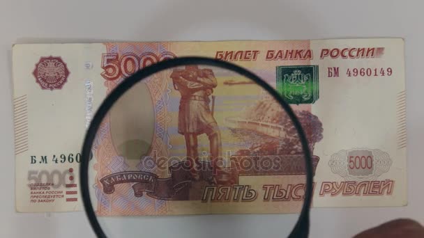 Approaching using a magnifying glass five-thousandth ruble bill. — Stock Video