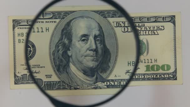 Approaching using a magnifying glass hundred dollar bill. — Stock Video