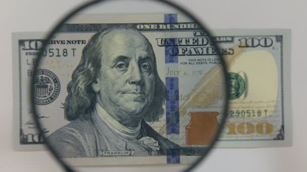 Benaderen met behulp van een vergrootglas honderd dollar bill. — Stockvideo