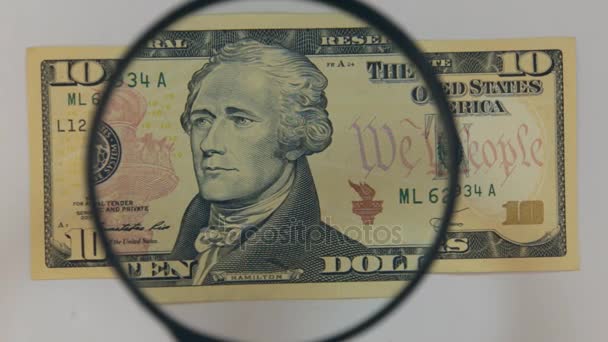 Approaching using a magnifying glass ten dollar bill. — Stock Video