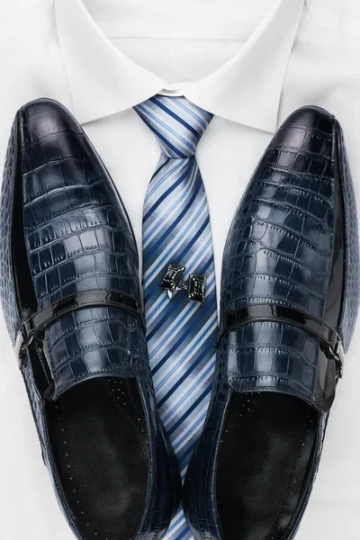 Pair of classic blue shoes standing on a shirt and tie. Men's fashion. — Stock Photo, Image