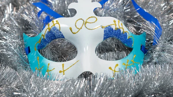 Christmas carnival mask on a silver tinsel background. Christmas masque with christmas tinsel . — Stock Photo, Image