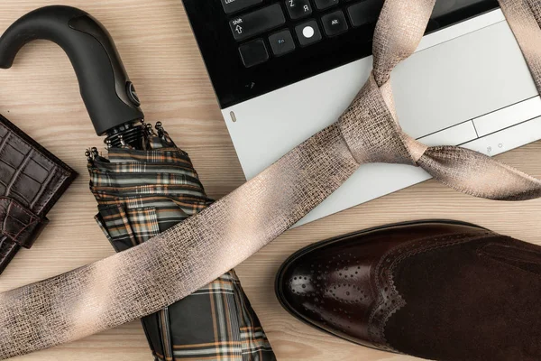 Mode en business, laptop, schoenen, manchetknopen, paraplu op een houten tafel als achtergrond. Van bovenaf bekijken. — Stockfoto