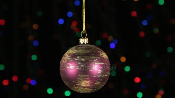 Nahaufnahme, die Drehung einer roten Weihnachtskugel, die an einem goldenen Seil hing. Weihnachts- und Neujahrsdekoration. — Stockvideo