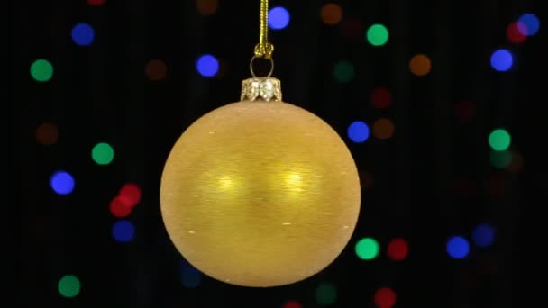 Detail, rotace žluté koule vánoční pověšen na zlaté lano. Vánoční a novoroční výzdoba.