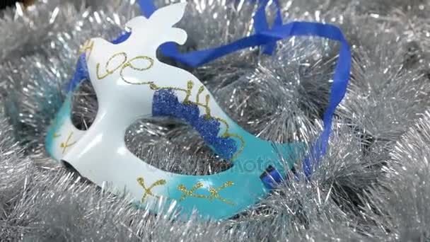 De rotatie van de close-up van een carnaval masker op een zilver klatergoud. Kerstmis achtergrond, klatergoud. — Stockvideo