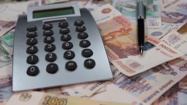 Close-up van de rotatie van de rekenmachine en balpen liggend op de roebel. — Stockvideo