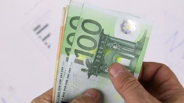 Man telt geld op de achtergrond van de diagrammen. Close-up. — Stockvideo